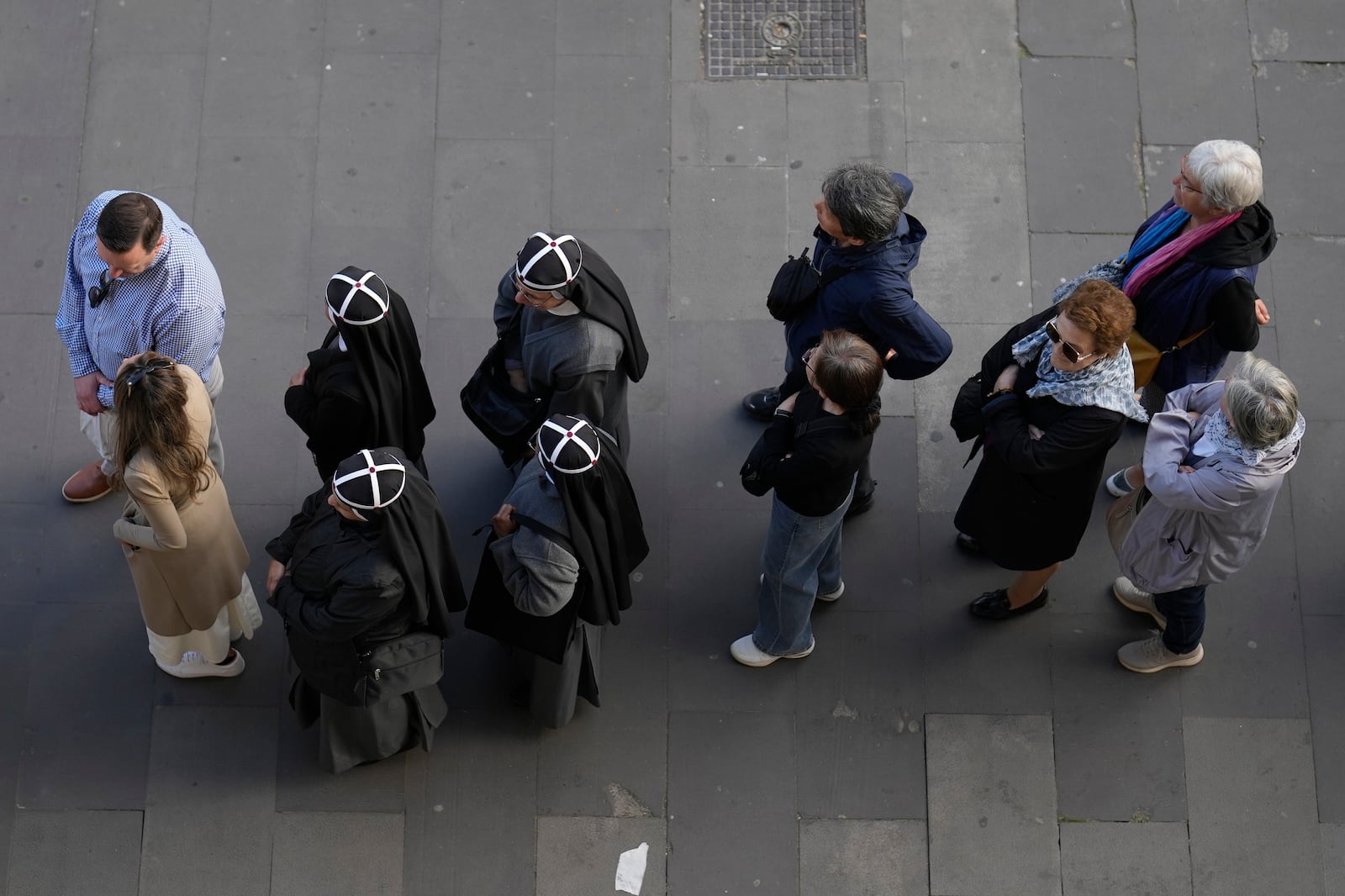 A group of four nuns, center left, wait in line with other people to view Pope Francis lying in state inside St. Peter's Basilica, at the Vatican, Thursday, April 24, 2025. (AP Photo/Markus Schrieber)