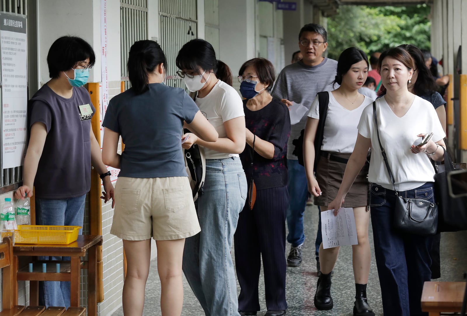 People prepare to vote at a polling station in Taipei, Taiwan, Saturday, July 26, 2025 as Taiwanese are casting their votes to determine whether to oust about one-fifth of their lawmakers, all from the opposition Nationalist Party, in elections. (AP Photo/Chiang Ying-ying)