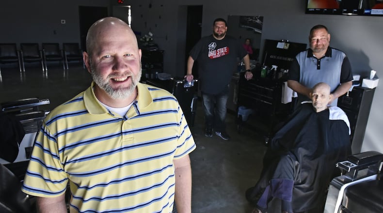 Owner Ryan Haynes, left, stands inside the Hamilton West Barber Shop with barbers Scott Page, middle, and Joe Templeton, cutting Tom Bell’s hair, on the first day in the new location Monday, Oct. 28, 2019. Steve Mallicote is also among the barbers in the shop. The new shop was formerly a car wash and is located at 186 N. Brookwood Avenue in Hamilton. NICK GRAHAM/STAFF