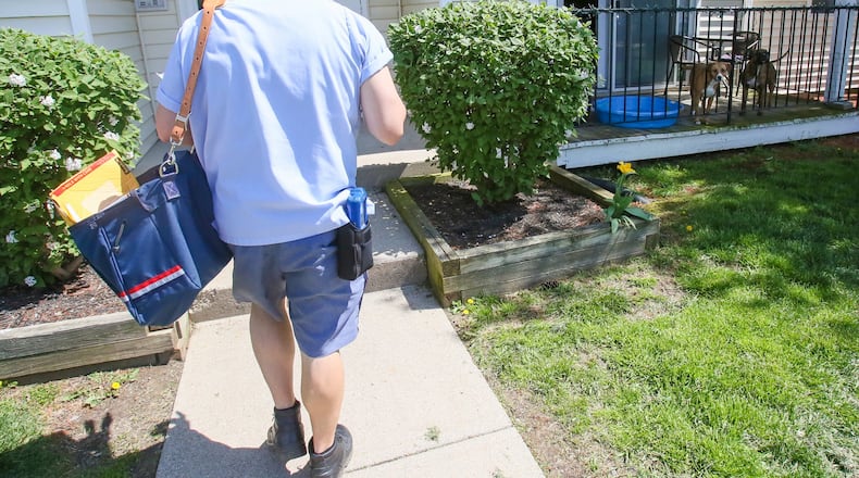 Mail carrier Jason Thompson delivers mail April 13 along his route at The Oaks of Woodridge apartments in Fairfield. GREG LYNCH / STAFF