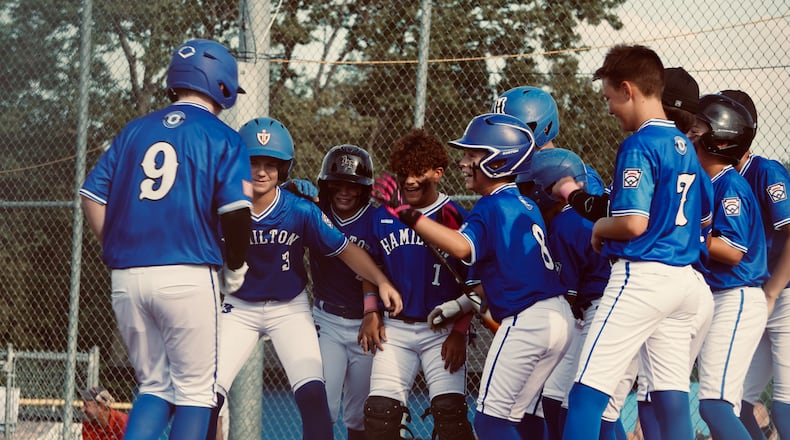 Hamilton West Side's Parker Moyer (9) is greeted by teammates at the plate after hitting a home run against Anderson Township in the Ohio Little League District 9 tournament Monday night at West Side Little League. Chris Vogt/CONTRIBUTED