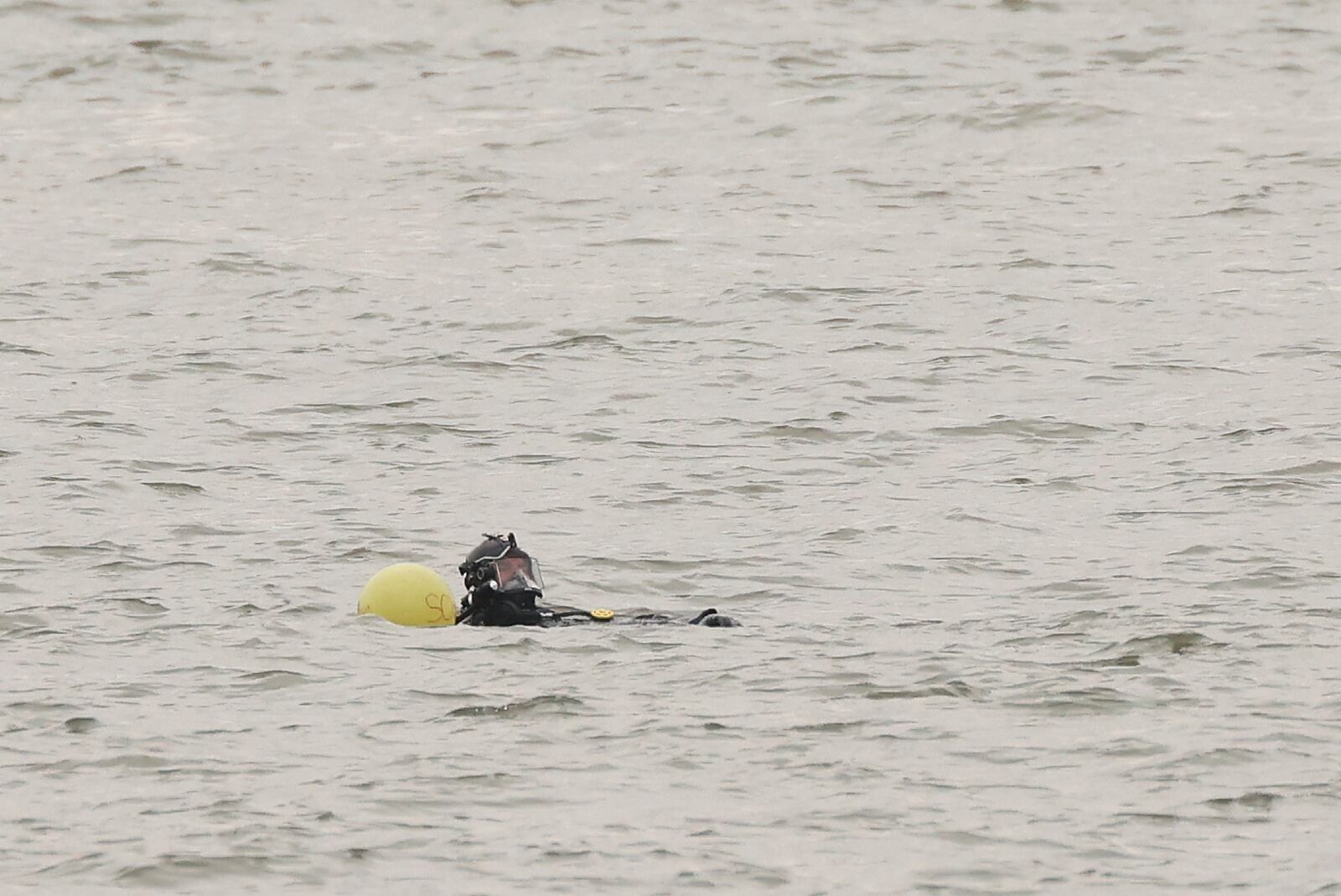 A New York Police Department scuba team diver prepares to search underwater, Friday, April 11, 2025, at the site where a sightseeing helicopter crashed a day earlier into the Hudson River in Jersey City, N.J. (AP Photo/Yuki Iwamura)