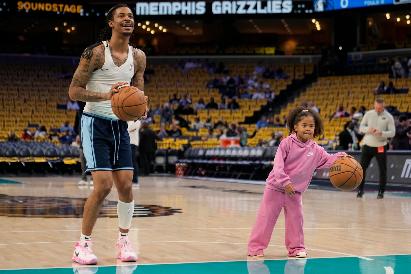 Memphis Grizzlies guard Ja Morant warms up with his daughter Kaari Morant before an NBA play-in tournament basketball game against the Dallas Mavericks, Friday, April 18, 2025, in Memphis, Tenn. (AP Photo/George Walker IV)