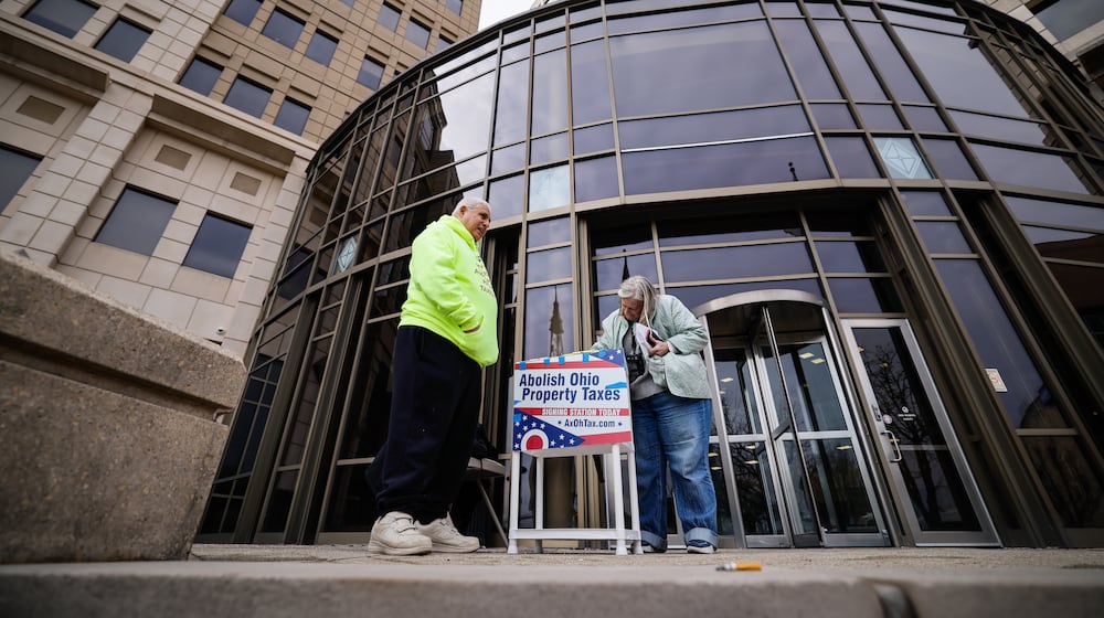 Ed Maloof, left, with AxOhioTax, gets signature from Donna Trueman Bryant as she goes to pay taxes Thursday, Feb. 26, 2026 at Butler County Government Services Center building on High Street in Hamilton. AxOhioTax was collecting signatures in order to put property tax repeal on the November ballot. NICK GRAHAM/STAFF