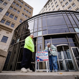 Ed Maloof, left, with AxOhioTax, gets signature from Donna Trueman Bryant as she goes to pay taxes Thursday, Feb. 26, 2026 at Butler County Government Services Center building on High Street in Hamilton. AxOhioTax was collecting signatures in order to put property tax repeal on the November ballot. NICK GRAHAM/STAFF