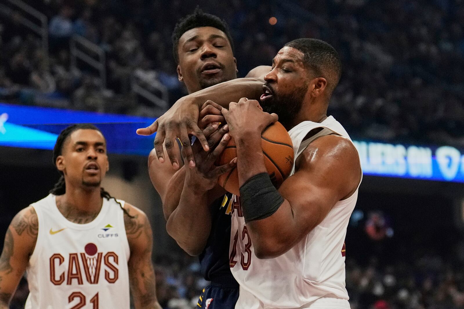 Indiana Pacers center Thomas Bryant, center, and Cleveland Cavaliers center Tristan Thompson (13) fight for control of the ball in the first half of an NBA basketball game Sunday, April 13, 2025, in Cleveland. (AP Photo/Sue Ogrocki)