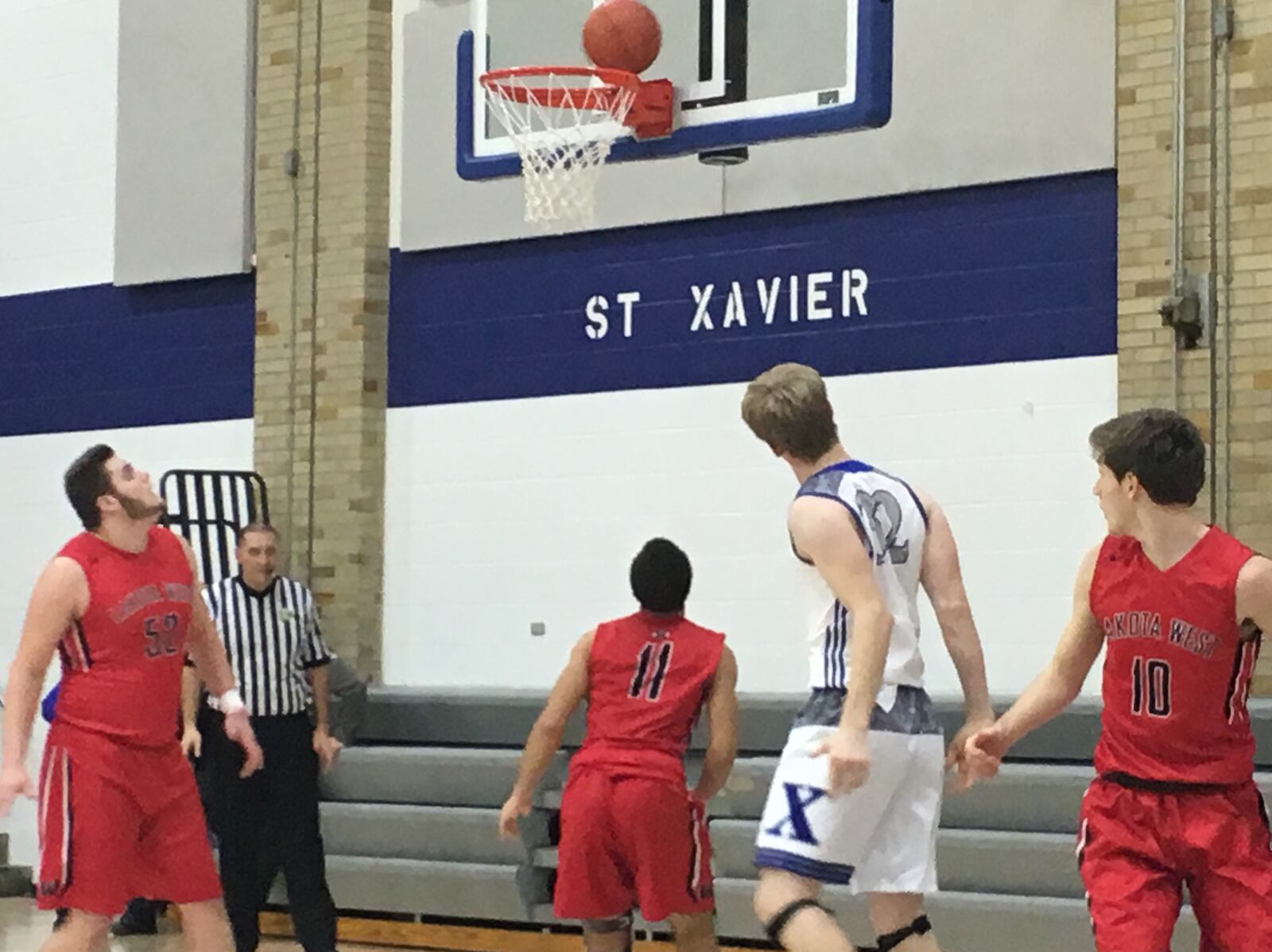 Lakota West’s Steven Faucheux (52), Je’seus Harris (11) and Bradley Groth (10) watch a shot by St. Xavier’s Luke Pellot (32) during Tuesday night’s game at Berning Gym in Springfield Township. RICK CASSANO/STAFF