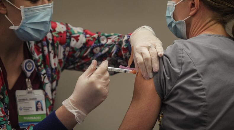 Premier Health pharmacist, Amanda Deskins gives a COVID shot to Miami Valley Hospital emergency room physician Dr. Cathy Marco. who was the first frontline worker at the hospital to be vaccinated Tuesday, Dec. 22, 2020. The COVID-19 vaccine arrived in Dayton Dec. 22, 2020 at Miami Valley Hospital. Doctors and nurses were the first to receive the vaccine. JIM NOELKER/STAFF