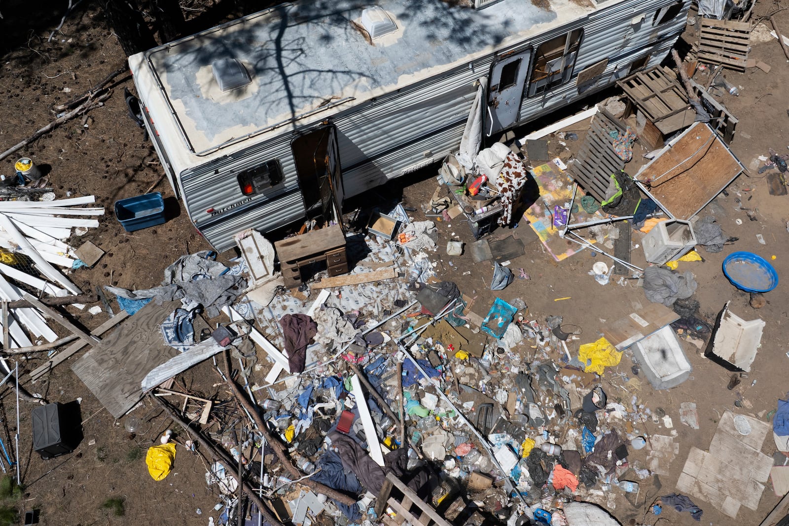 Debris lies scattered around a trailer at a homeless encampment in Deschutes National Forest, Thursday, May 1, 2025, near Bend, Ore. (AP Photo/Jenny Kane)