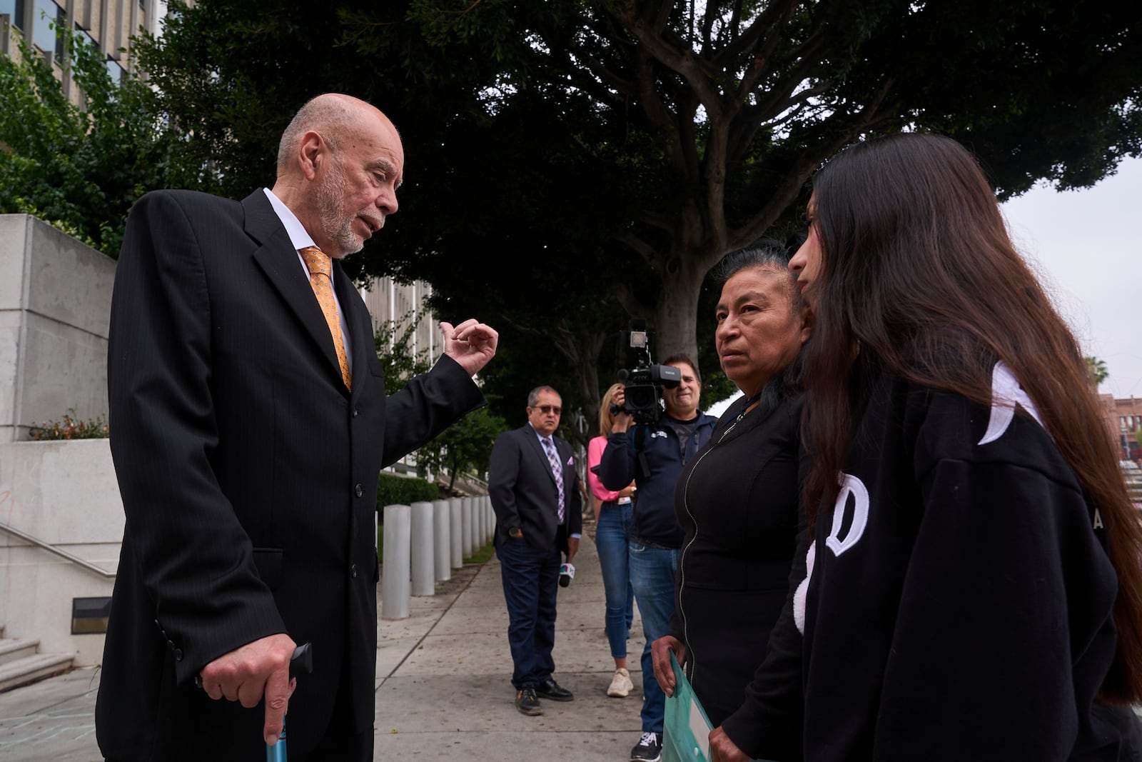Civil Rights Attorney Luis Carrillo, left, stands with clients, Margarita Flores, second from right, and her daughter, Estrella Rosas, far right, outside the ICE Los Angeles Staging Facility looking to find her daughter, Andrea Velez, a U.S. citizen who was detained by federal agents in an immigration raid downtown Los Angeles, on Wednesday, June 25, 2025. (AP Photo/Damian Dovarganes)