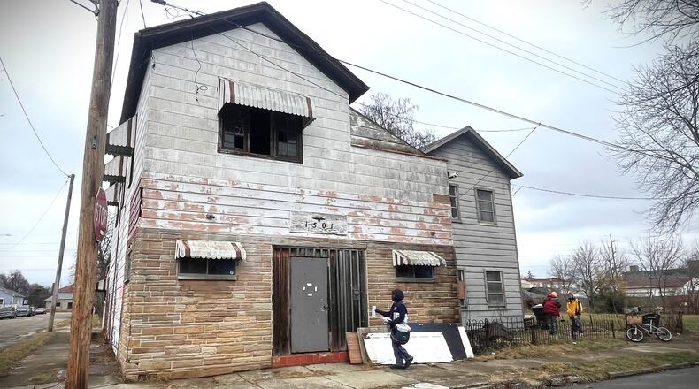 A postal worker delivers mail to a property in East Dayton that auditor records show owes more than $24,000 in unpaid taxes. CORNELIUS FROLIK / STAFF