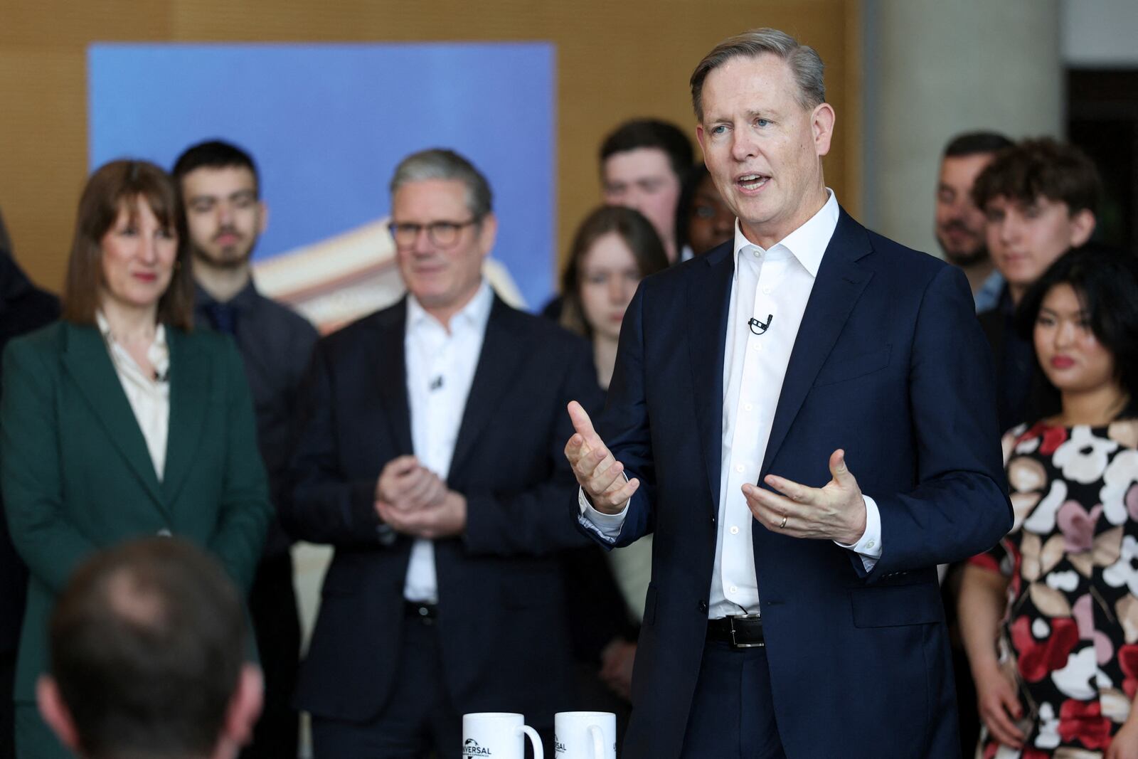 President of Comcast Corporation Michael Cavanagh speaks next to British Prime Minister Keir Starmer and Chancellor of the Exchequer Rachel Reeves at an announcement that U.S. media giant Comcast Corp will build its first Universal theme park and resort in Europe, opening in 2031, during a visit to Bedford, north of London, Wednesday April 9, 2025. (John Sibley/Pool Photo via AP)