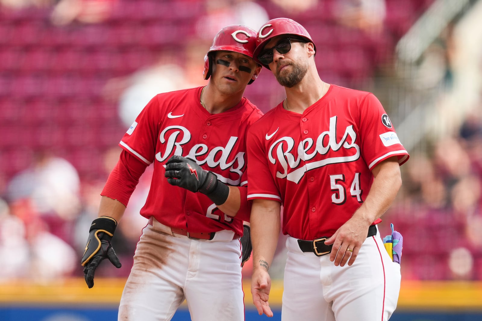 Cincinnati Reds' TJ Friedl celebrates with first base coach Collin Cowgill (54) after hitting a single during the seventh inning of a baseball game against the Pittsburgh Pirates, Thursday, Sept. 25, 2025, in Cincinnati. (AP Photo/Jeff Dean)