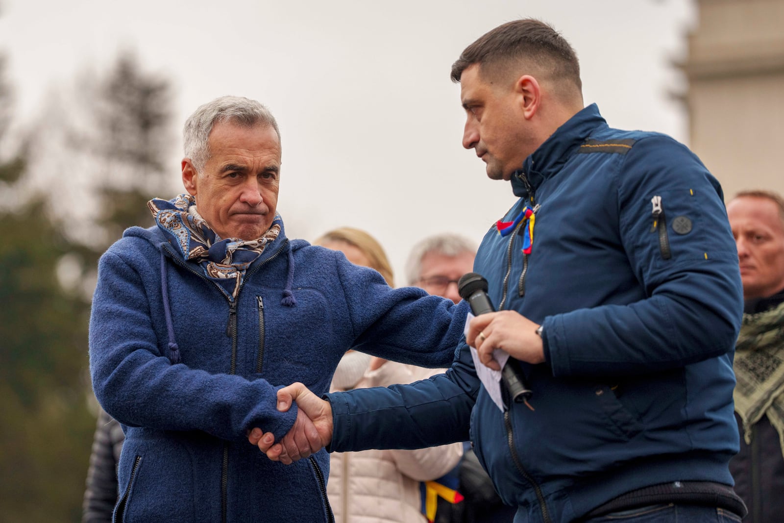 FILE - Calin Georgescu, left, the winner of the first round of presidential elections which were annulled, shakes hands with George Simion, presidential candidate for the Alliance for the Union of Romanians (AUR) during a protest calling for the resignation of the country's Prime Minister Marcel Ciolacu, in Bucharest, Romania, Saturday, March 1, 2025. (AP Photo/Andreea Alexandru, File)