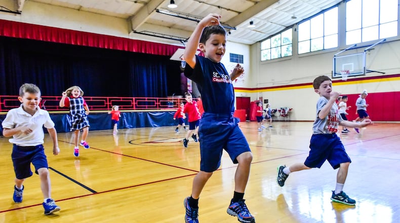 Second-grade students, with Marco Kimener jumping, run in the gymnasium at St. John XXIII Catholic Elementary School in Middletown that has a newly installed air conditioning system for the start of the school year. The former Fenwick High School gymnasium has not had air conditioning since it was built in the early 1960s. NICK GRAHAM/STAFF