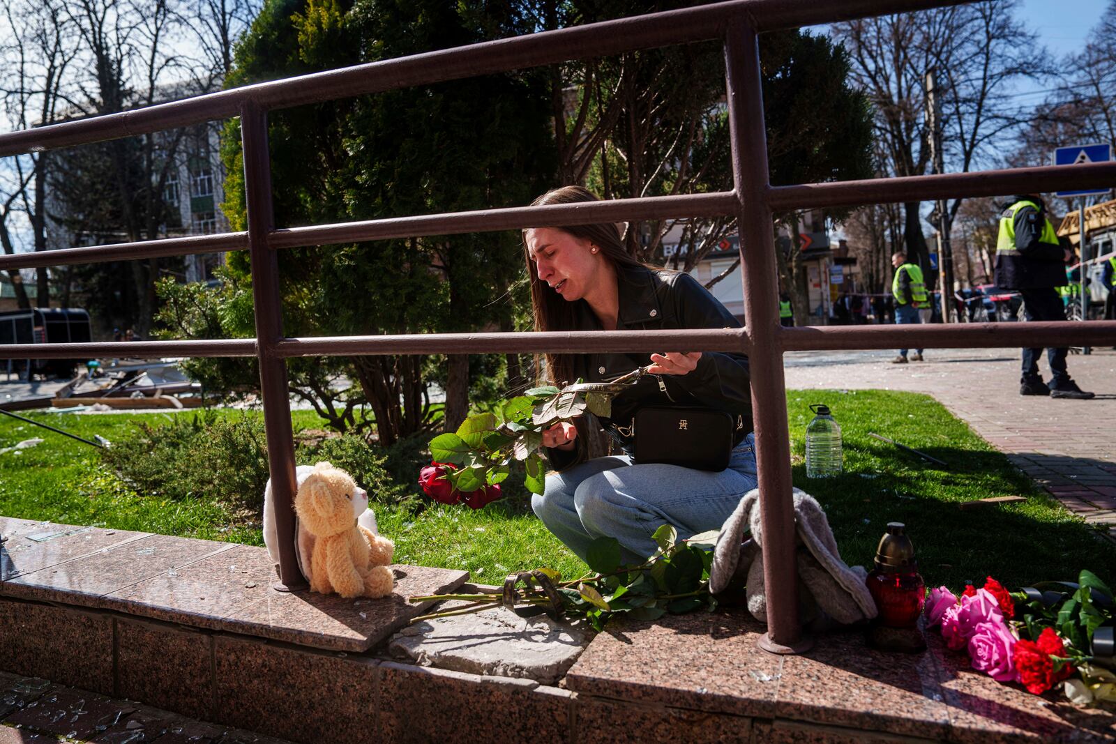 Kateryna Sitak, 23, a teacher, cries while laying flowers and toys on a site of a Russian missile strike in Sumy, Ukraine, Monday, April 14, 2025. (AP Photo/Evgeniy Maloletka)