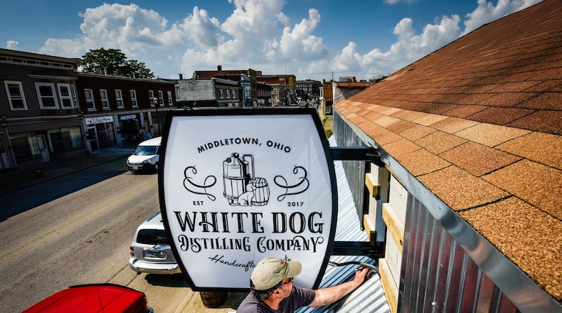 Jim Edwards with Digital Visuals installs signage outside of White Dog Distilling Company on Central Avenue in Middletown.
