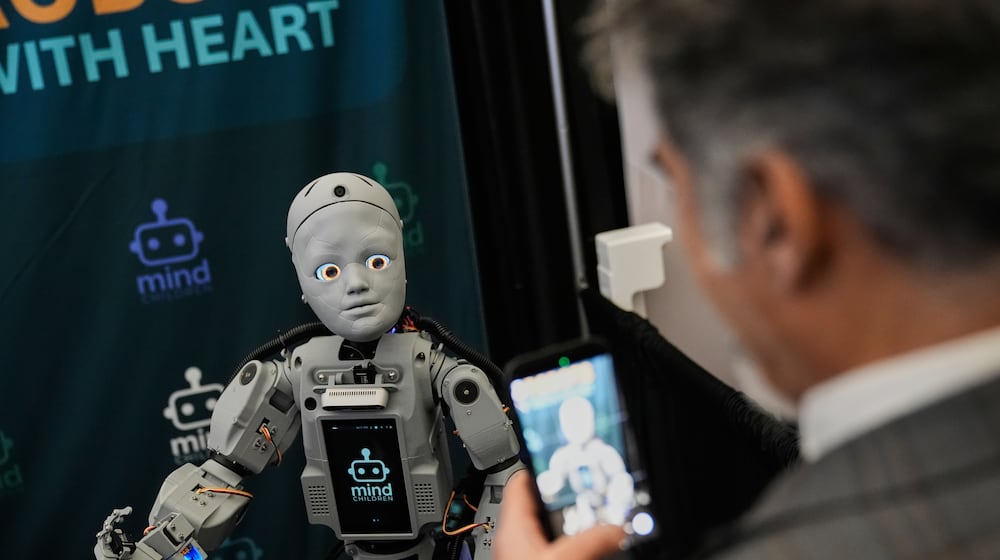 A man records a humanoid robot inside the exhibition room at the Humanoids Summit, Thursday, Dec. 11, 2025, in Mountain View, Calif. (AP Photo/Godofredo A. Vásquez)