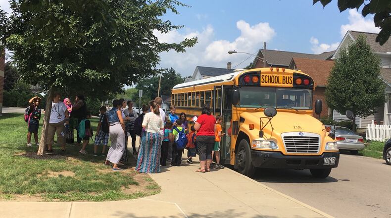 JEREMY P. KELLEY / STAFF ORIGINAL CUTLINE: Students board a school bus outside Ruskin Elementary school in Dayton as teachers and school staff monitor the area.