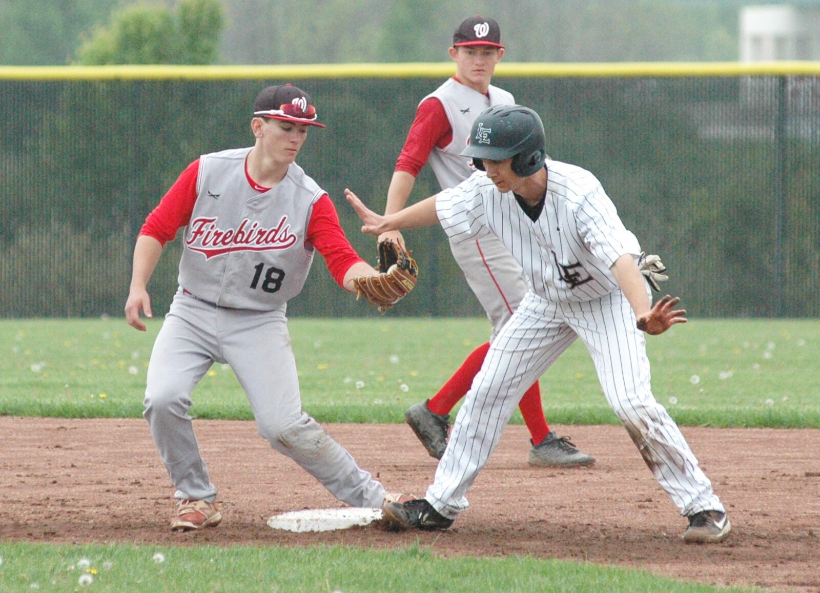 Lakota East’s Will Koger is safe at second base ahead of the throw to Lakota West’s Cooper Walker on Saturday afternoon during a Greater Miami Conference baseball game at East. West won 5-3 in nine innings. RICK CASSANO/STAFF