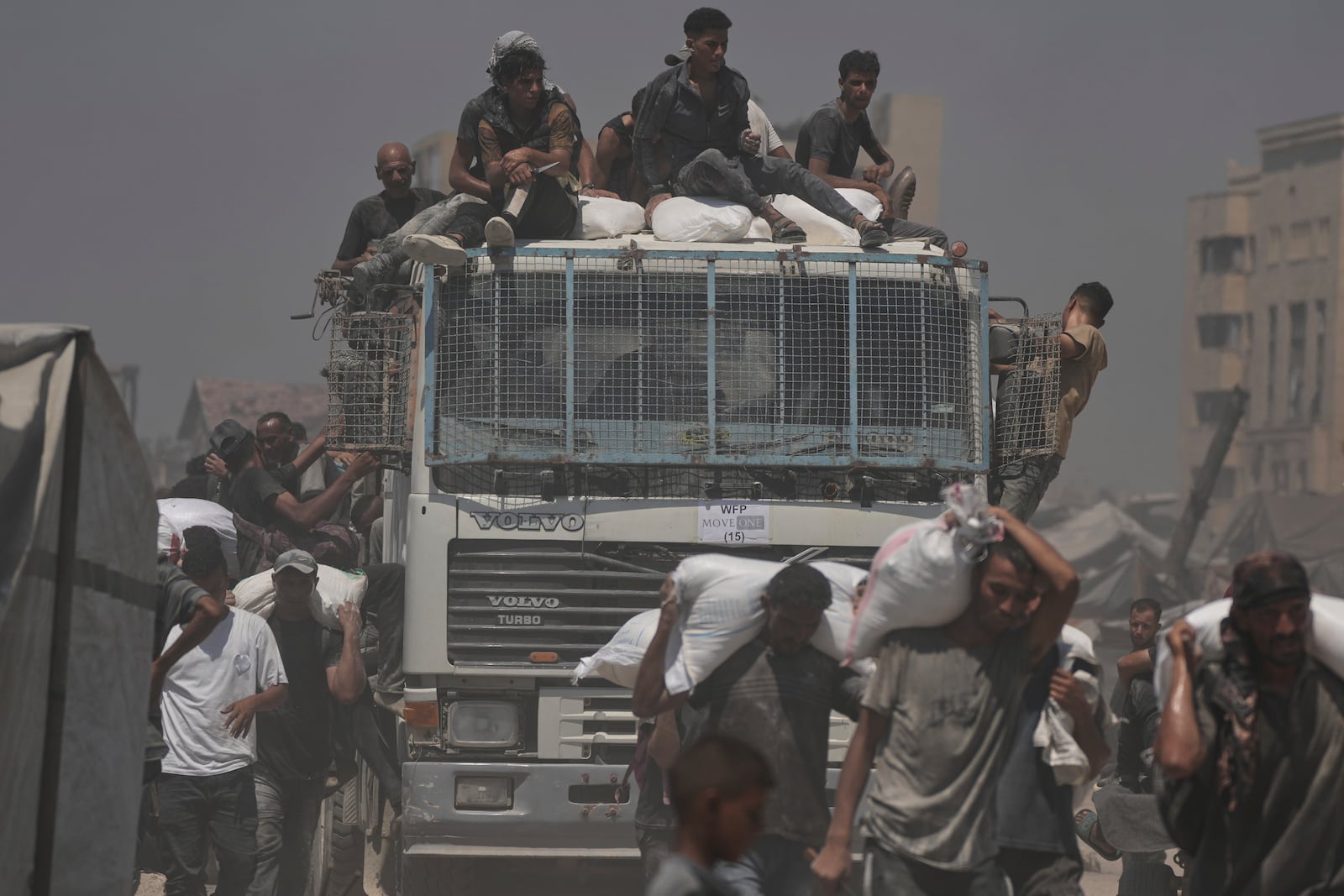 Palestinians carry sacks of flour unloaded from a humanitarian aid convoy that reached Gaza City from the northern Gaza Strip, Sunday, July 27, 2025. (AP Photo/Jehad Alshrafi)