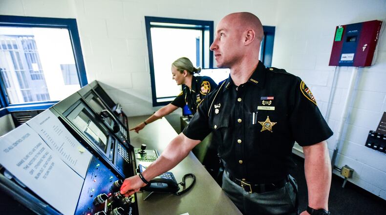 Butler County Sheriff’s Office corrections officers Waylon Thomas and Hannah McCarthy stand in the control room of the old Butler County Court Street Jail that was re-opened recently, in part because a new law takes effect July 1 that prohibits judges from sending felony five offenders to prison. Sheriff’s Chief Deputy Tony Dwyer said they also have more contract prisoners than local ones, a situation that requires a careful balancing act between pulling in more revenue for boarding inmates and having to hire more people full-time. One floor of the jail is in operation and another floor is ready for new inmates. NICK GRAHAM/STAFF