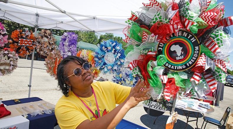 Donna Oliver, from Oh My Wreath, hangs a Juneteenth wreath at her booth Saturday, June 15, 2024 during the annual Juneteenth and Fatherfest Celebration. BILL LACKEY/STAFF