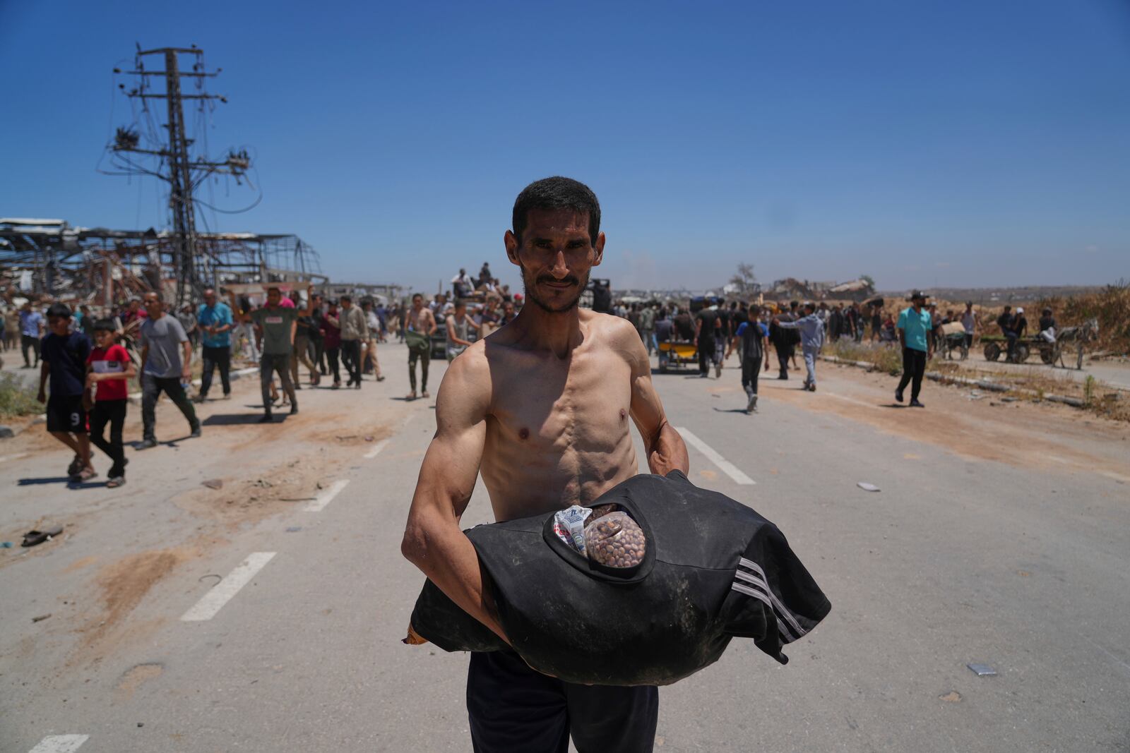 A Palestinian man carries food in his T-shirt after receiving aid from the Gaza Humanitarian Foundation, a U.S.-backed organization approved by Israel, in Khan Younis, southern Gaza Strip, on Thursday, May 29, 2025. (AP Photo/Abdel Kareem Hana)