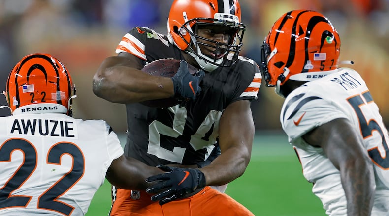 Cleveland Browns running back Nick Chubb (24) carries the ball with Cincinnati Bengals cornerback Chidobe Awuzie (22) and linebacker Germaine Pratt (57) defending during the first half of an NFL football game in Cleveland, Monday, Oct. 31, 2022. (AP Photo/Ron Schwane)