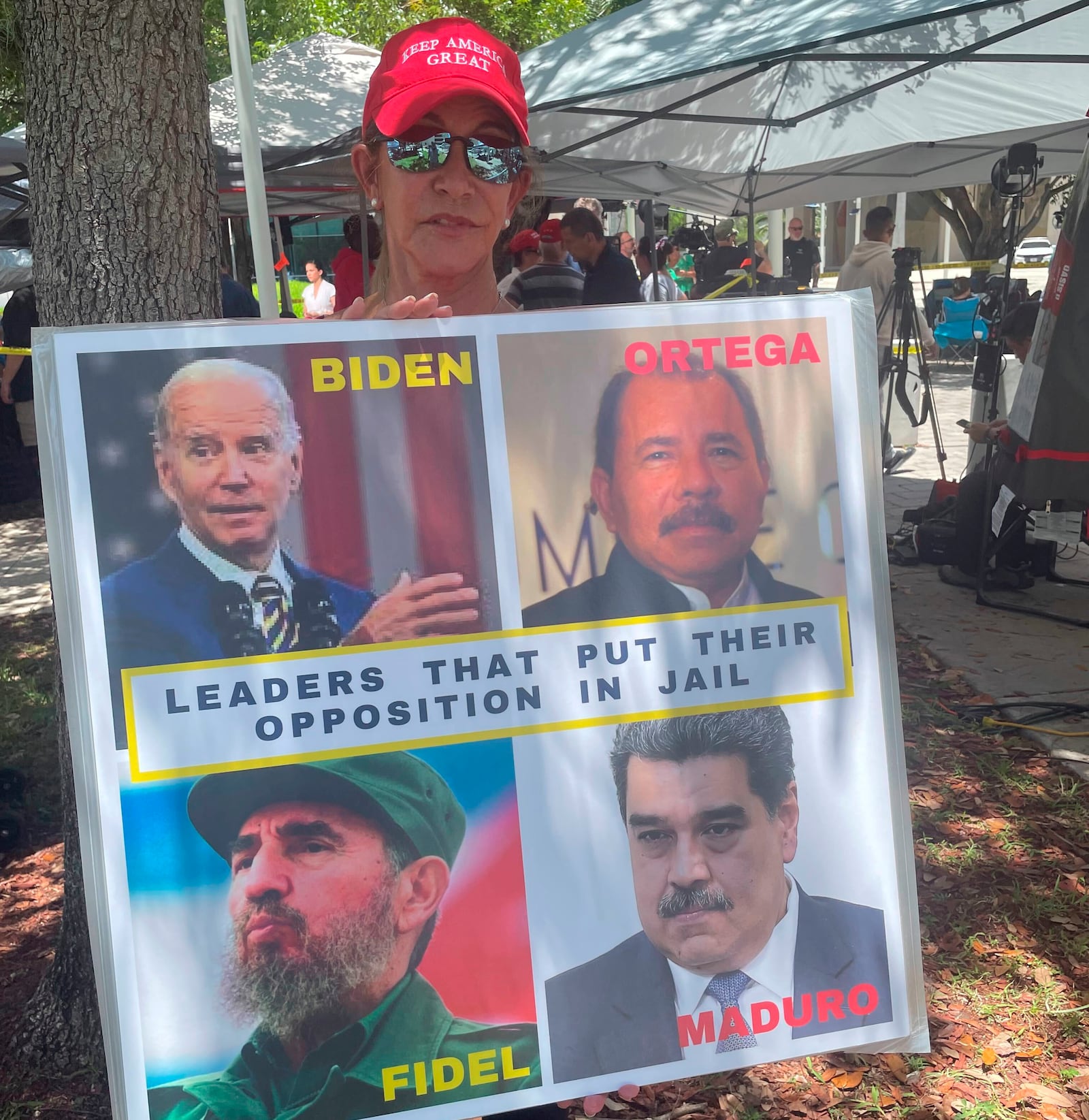FILE - Madelin Munilla, 67, who came to Miami as a child when her parents fled Fidel Castro's Cuba, holds up a sign comparing President Joe Biden to Castro and other Latin American leaders at a rally outside the Wilkie D. Ferguson Jr. U.S. Courthouse, June 13, 2023, in Miami. (AP Photo/Joshua Goodman, File)