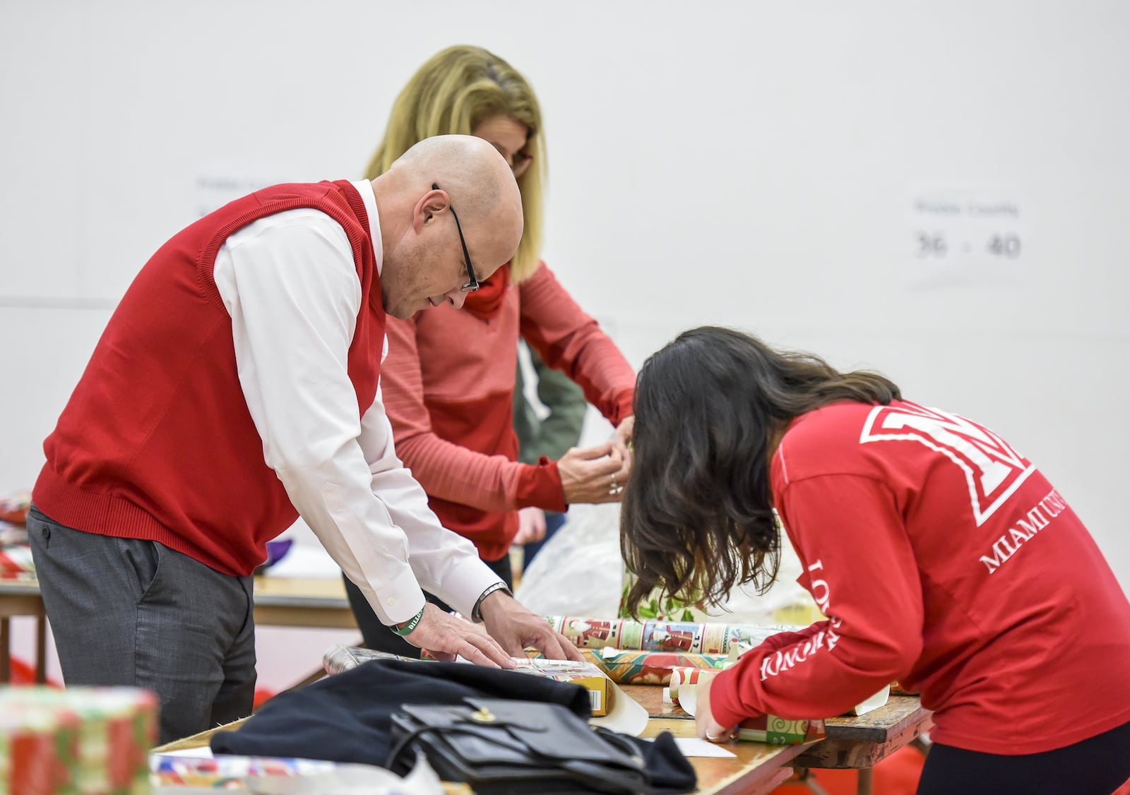 Miami University President Gregory Crawford and his wife, Renate, along with Miami freshman, Rebecca Dela Cruz, right, wrap gifts for the Miami Holiday Project on Tuesday, Dec 13, in Phillips Hall in Oxford. NICK GRAHAM/STAFF
