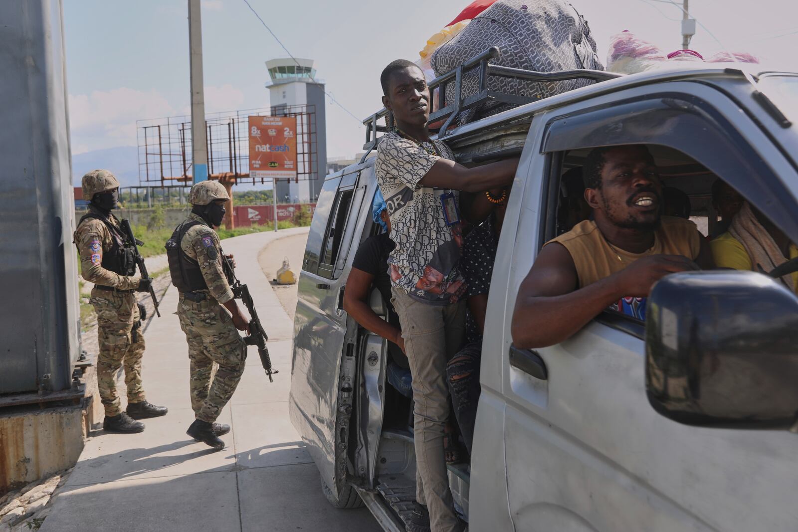 Commuters pass by police patrolling an intersection in Port-au-Prince, Haiti, Friday, May 9, 2025. (AP Photo/Odelyn Joseph)
