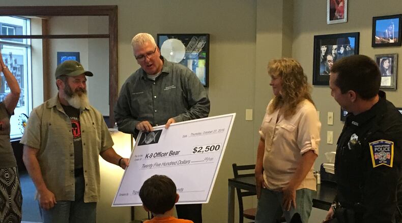 Middletown Police Chief Rodney Muterspaw accepts a $2,500 check from Triple Moon Coffee Shop co-owner Heather Gibson. The money will be used to purchase a protective vest for Bear, a canine officer.