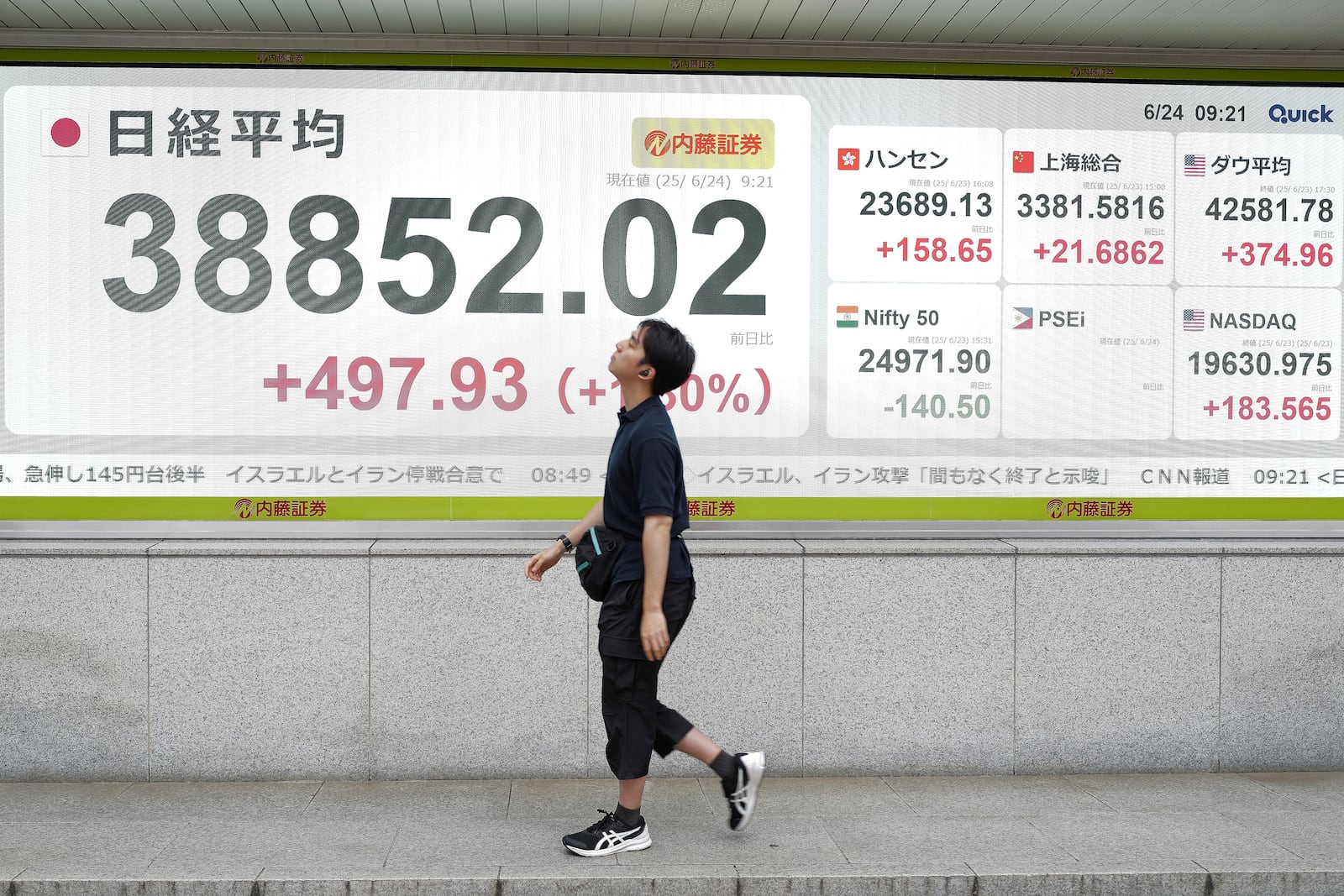 A person walks in front of an electronic stock board showing Japan's Nikkei index at a securities firm Tuesday, June 24, 2025, in Tokyo. (AP Photo/Eugene Hoshiko)