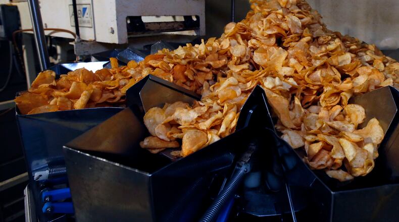 Freshly seasoned potato chips tumble into the bagging machine at Mikesell’s. TY GREENLEES / STAFF