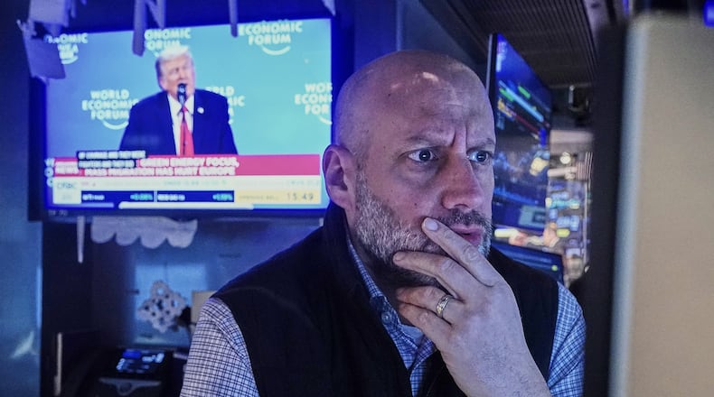 Specialist Meric Greenbaum works at his post on the floor of the New York Stock Exchange, as a television shows President Donald Trump speaking at the World Economic Forum, Wednesday, Jan. 21, 2026. (AP Photo/Richard Drew)