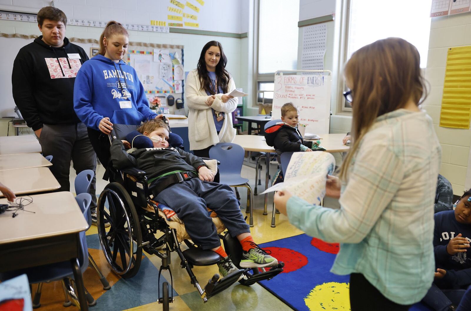 Rydder Ames, a 7-year-old battling a rare brain disease called DMG, visited his second-grade classroom at Brookwood Elementary Tuesday, Jan. 24, 2023 to receive handmade birthday cards from his classmates and listen to a story read by his teacher Piper Van Der Veer. Classmate Bailey Johnson, right, read her card to him during the visit. NICK GRAHAM/STAFF