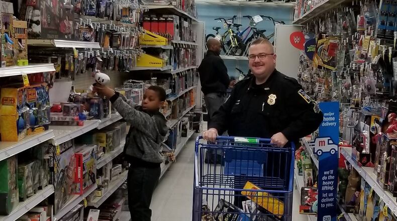 Sgt. Cris Kelly helps a young child shop during the Middletown Division of Police Mike Davis Christmas With A Cop program this month at Meijer.