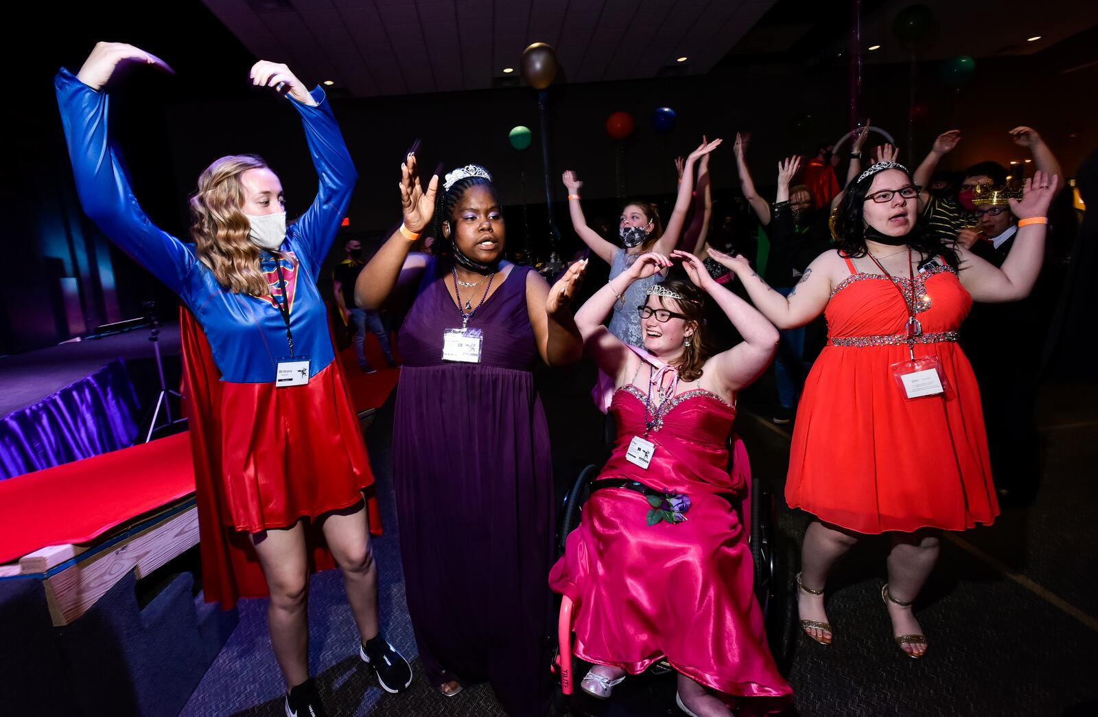 Left to right: Volunteer Brittany Bottles dances with Jessica Holmes, Elley Ferrell and Sara Woods during the "One Special Night" special needs prom Friday, March 26, 2021 at Berachah Church in Middletown. Attendees were treated like royalty with each person getting crowned king or queen on stage, dancing, hot air balloon glow and a performance by Cincinnati Circus. The them was Heroes Unite with many volunteers dressed as superheroes. NICK GRAHAM / STAFF