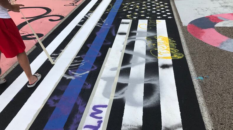 A Lakota West High School student's pro-police art work - depicting the "thin blue line" on an American flag painting - in a parking space was vandalized. Both school and police leaders criticized the crime. Pictured, students, school staffers restoring the artwork, which had included anti-police profanity. (Provided Photo\Journal-News)