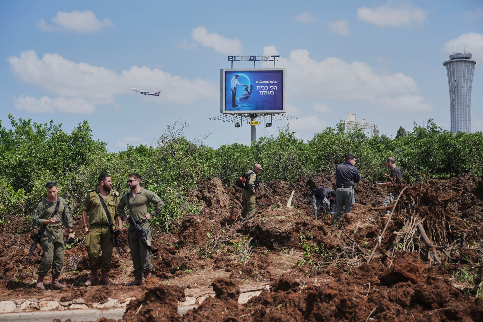 Israeli security forces inspect the site where the Israeli military said a projectile fired by Yemen's Houthi rebels landed in the area of Ben Gurion International Airport near Tel Aviv, Israel, on Sunday, May 4, 2025. (AP Photo/Ohad Zwigenberg)