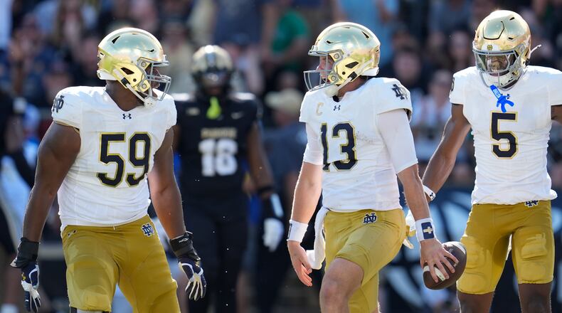 Notre Dame quarterback Riley Leonard (13) celebrates his touchdown down with teammates Aamil Wagner (59) and Beaux Collins (5) during the first half of an NCAA college football game against Purdue in West Lafayette, Ind., Saturday, Sept. 14, 2024. (AP Photo/Michael Conroy)