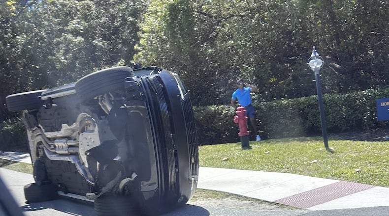 Golfer Tiger Woods stands by his overturned vehicle in Jupiter Island, Fla., on Friday, March 27, 2026. (AP Photo/Jason Oteri)