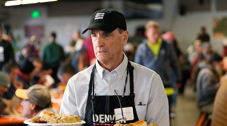 FILE - Volunteer Brent Cohen carries plates of food to guests during the annual Thanksgiving banquet at the Denver Rescue Mission on Nov. 22, 2023, in Denver. (AP Photo/David Zalubowski, File)