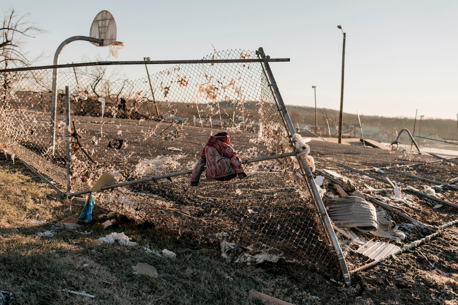 Debris including a small jacket is strewn across a damaged fence in Dawson Springs, Ky., on Monday, Dec. 13, 2021, where a tornado flattened much of the town on Friday night. After grimly fluctuating death tolls since Friday’s devastating swarm of tornadoes, Gov. Andy Beshear of Kentucky said on Monday that there were 64 confirmed deaths in the state, though he expected that number to rise as crews continued to search through the ruins. (William Widmer/The New York Times)
