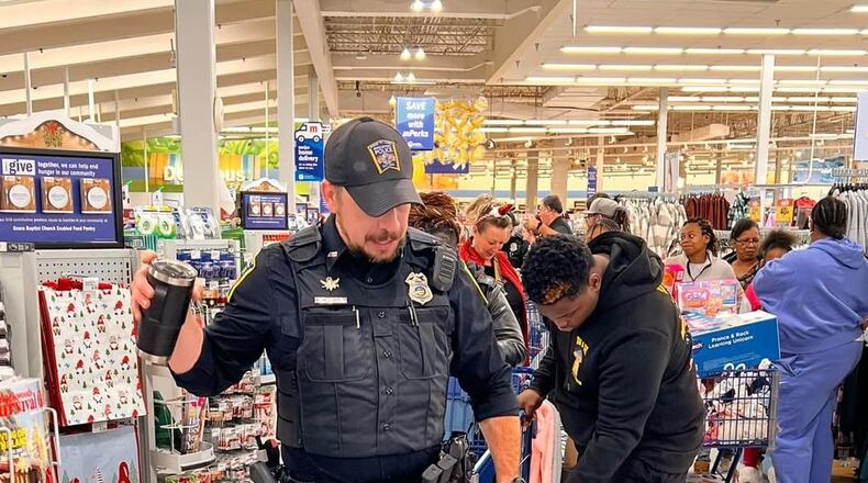 Middletown Division of Police officer Marco Caito helps children shop last week at Meijer during the Mike Davis Christmas with a Cop program. SUBMITTED PHOTO
