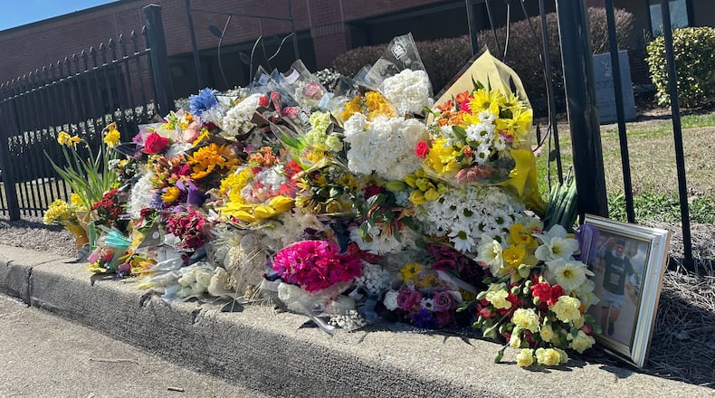 Flowers lie along a fence outside North Hall High School in Gainesville, Ga., on Monday, March 9, 2026. (AP Photo/Emilie Megnien)