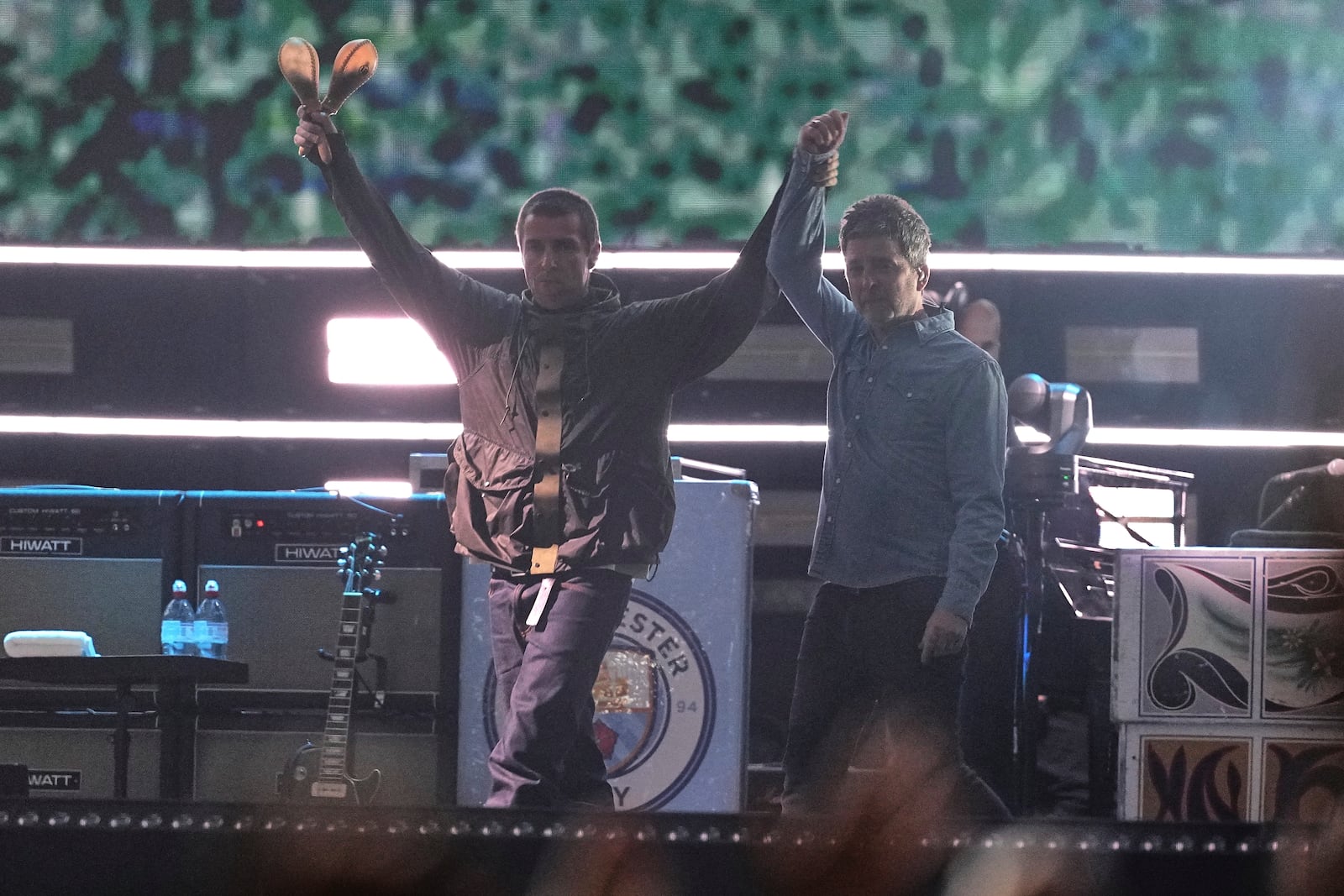 Liam Gallagher, left, holds the hand aloft of Noel Gallagher from the band Oasis as they perform during their reunion concert on Friday, July 4, 2025, in Cardiff. (Photo by Scott A Garfitt/Invision/AP)