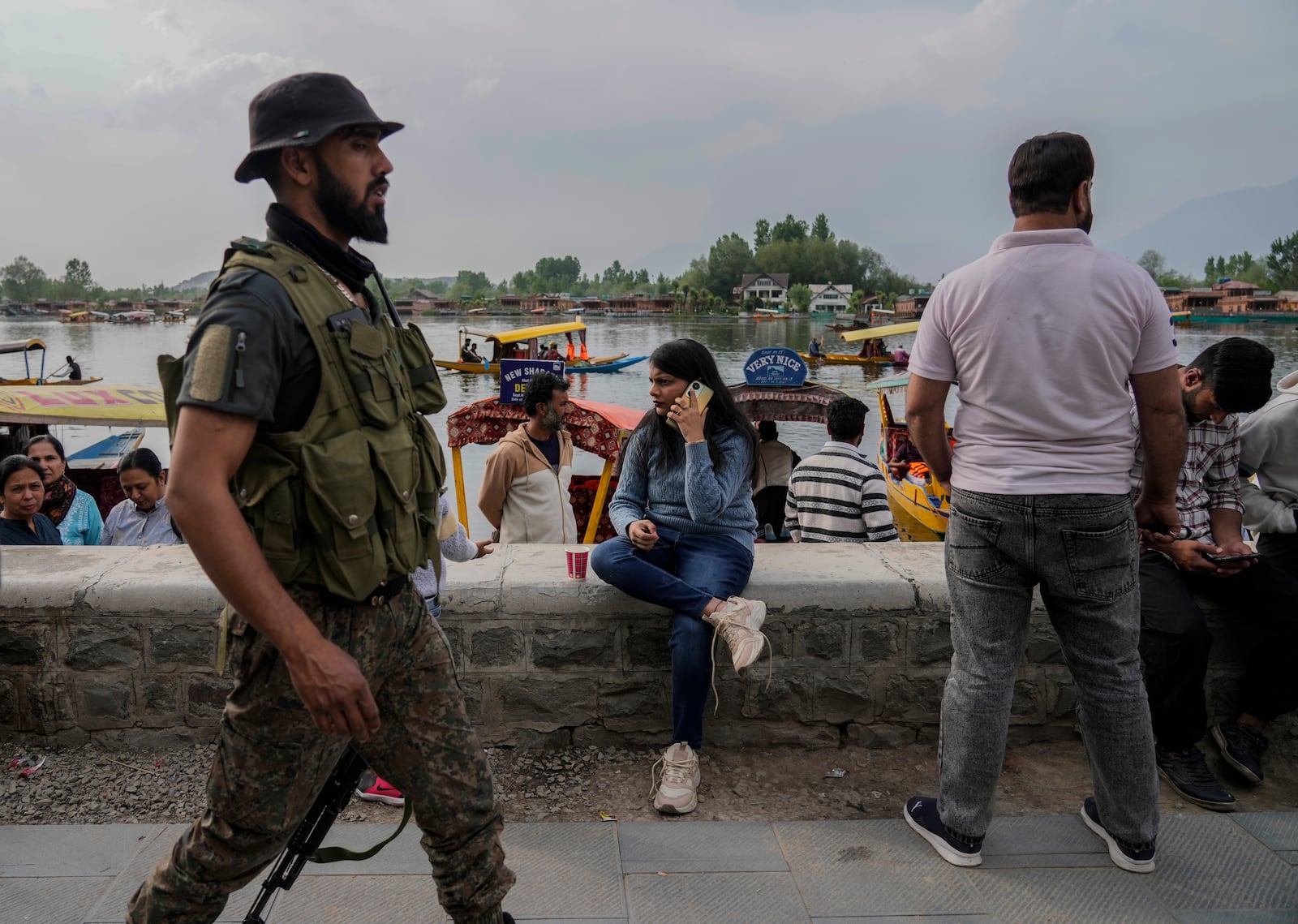 An Indian tourist woman talk to her cell phone as Jammu and Kashmir Special Operation Group (SOG) personnel patrol at a Dal Lake in Srinagar, Indian controlled Kashmir,Tuesday, April. 22, 2025. (AP Photo/Mukhtar Khan)