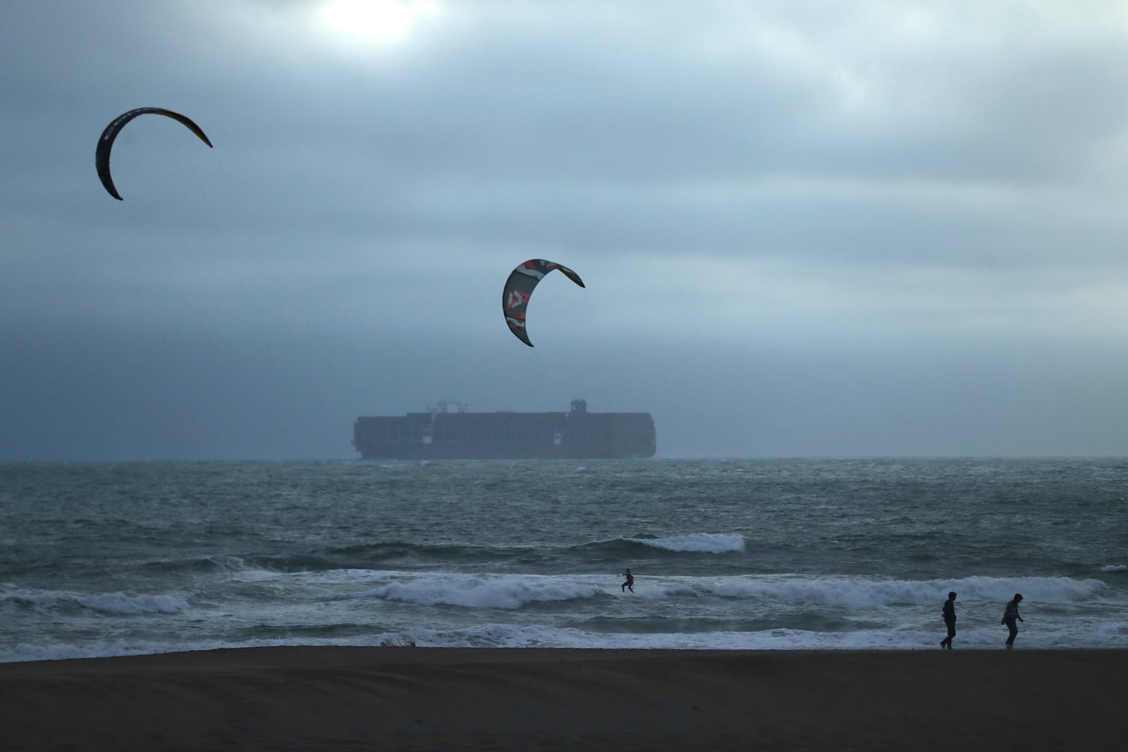 During a tsunami advisory triggered by an underwater earthquake off the coast of Russia, a pair of kite surfers recreate near two beach walkers at Ocean Beach in San Francisco on Tuesday, July 29, 2025. (Scott Strazzante/San Francisco Chronicle via AP)